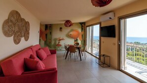 Una sala de estar moderna con un sofá rojo, un comedor y un balcón con vistas.