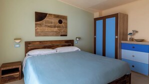 Un dormitorio con cama de madera, mesita de noche, lámpara de pared, armario y un adorno en la pared.