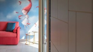 Una sala de estar moderna con un sofá rojo, una mesita redonda y un mural de una niña de cabello rojo.