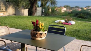 Una mesa con una cesta tejida de flores, una silla y vista al mar.