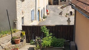 Un patio con edificios de piedra, una cerca de madera y plantas en macetas.
