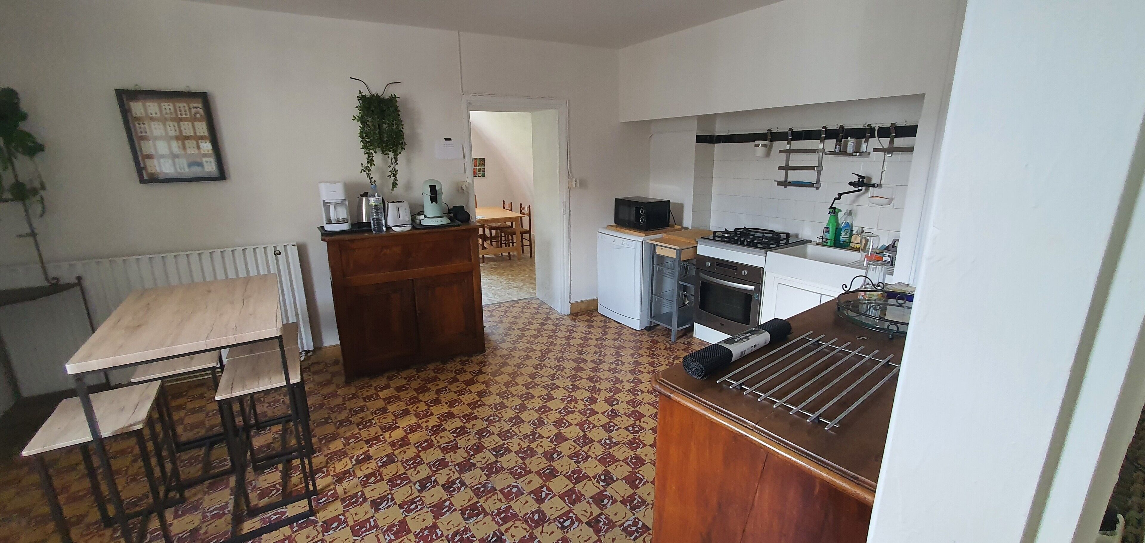 A kitchen with a radiator, a wooden table, a microwave, and a sink.