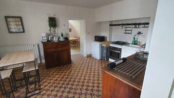 A kitchen with a radiator, a wooden table, a microwave, and a sink.