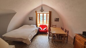 Un dormitorio con una cama, una silla roja, una mesa de madera y un aparador.