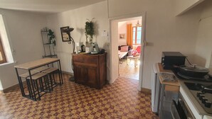 Una cocina con piso estampado, una mesa de madera con taburetes, un radiador y una estufa.