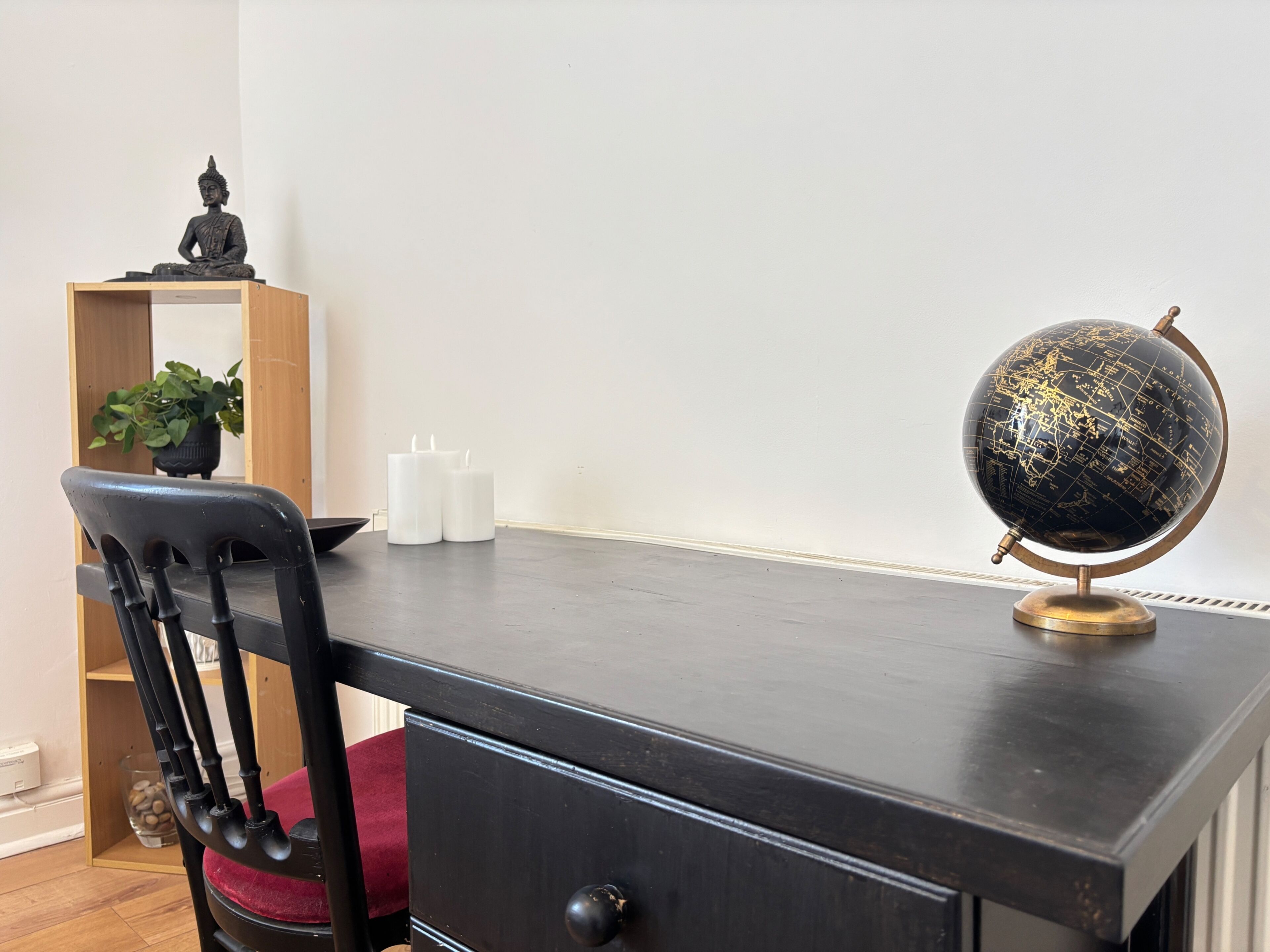 A desk with a globe, candles, and a Buddha statue.