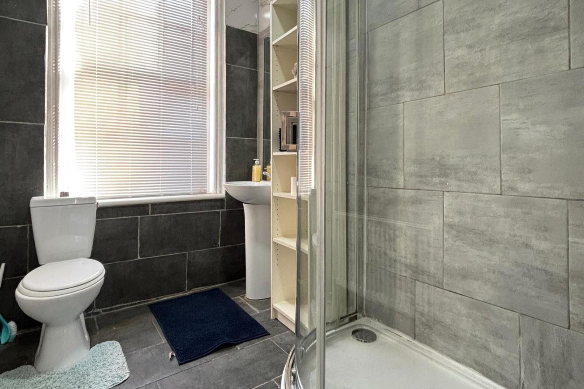 A bathroom with a toilet, sink, and shower area.