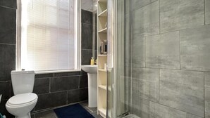 Een badkamer met toilet, wastafel en douche.