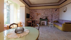 A room with a fireplace, a sofa, a dining table, and a chair. - Apartment no. 3 ( CIN: IT008031B423CF7JSW Citra 008031-LT-1489 ) (Imperia)