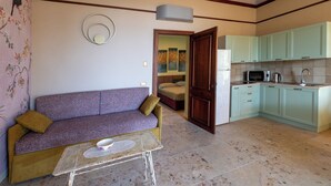 A living room with a sofa, a coffee table, and a kitchen area with cabinets and appliances. - Apartment no. 3 ( CIN: IT008031B423CF7JSW Citra 008031-LT-1489 ) (Imperia)
