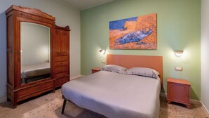 Ein Schlafzimmer mit einem großen Bett, einem Holzschrank und einem Bild an der Wand.