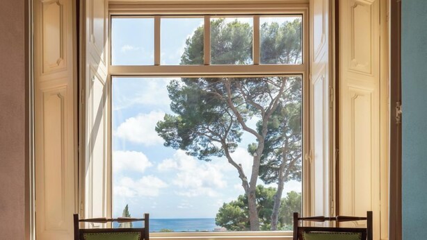 A room with two chairs facing a large window with a view of trees and the sea. - APARTMENT No. 7 ( CIN: IT008031B4KQZ5NP5U Citra 008031-LT-1493 ) (Imperia)