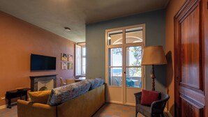 A living room with a sofa, a television, a fireplace, and a view of the outdoors through a glass door. - APARTMENT No. 7 ( CIN: IT008031B4KQZ5NP5U Citra 008031-LT-1493 ) (Imperia)