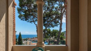 A balcony with a table set for two, overlooking a coastal view with trees and buildings. - APARTMENT No. 7 ( CIN: IT008031B4KQZ5NP5U Citra 008031-LT-1493 ) (Imperia)