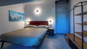 Een slaapkamer met een bed, nachtlampjes, een nachtkastje, een deur en een metalen plank.