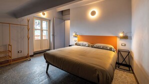 A bedroom with a large bed, a wardrobe, a coat rack, and a window with natural light. - APARTMENT No. 9 ( CIN: IT008031B4324MG4G6 Citra 008031-LT-1495 ) (Imperia)
