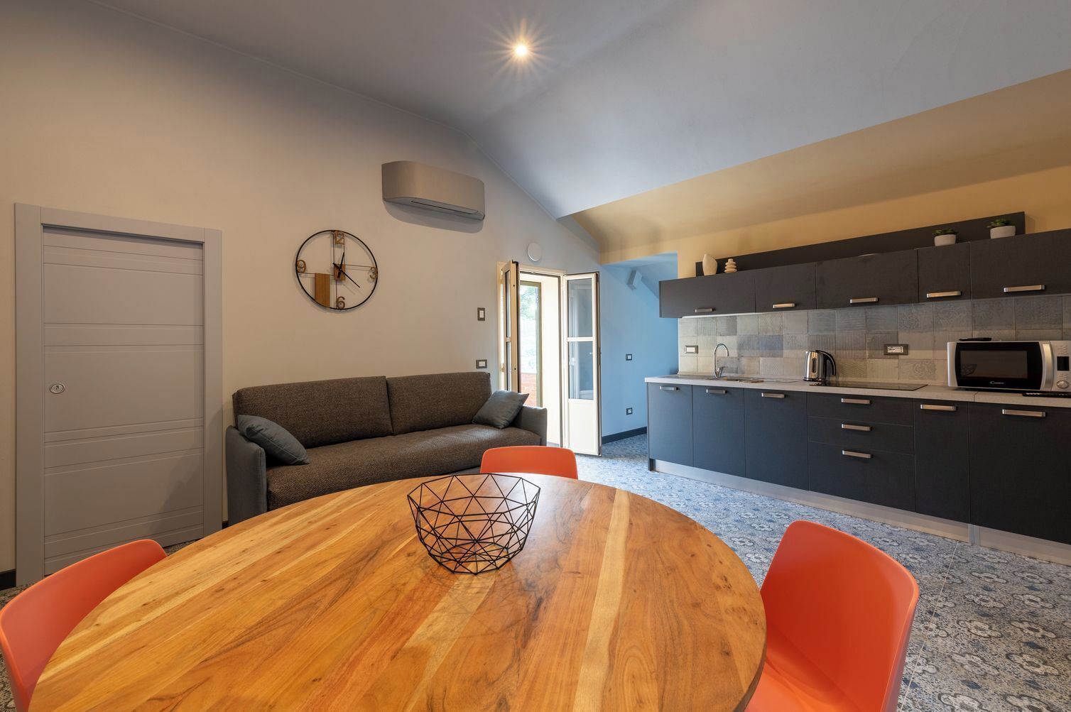 A modern kitchen with dark cabinets, a microwave, and a kettle.