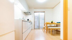 A compact kitchen with a refrigerator, stove, and a dining area with a table and chairs. - Kayo, Nijo Minami, 6 minutes walk from Nijo Station, quiet house (Kyoto)