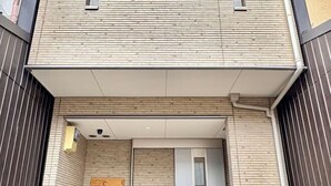 A modern building entrance with a wooden facade, a signboard, and a covered entrance area. - Kayo, Nijo Minami, 6 minutes walk from Nijo Station, quiet house (Kyoto)