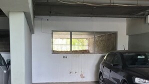 A parking garage with concrete floors and walls, a window with bars, and a parked car. - Vistá Piscaderá (Willemstad)