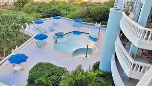 A rooftop pool with lounge chairs and umbrellas, surrounded by greenery and a white railing. - Vistá Piscaderá (Willemstad)