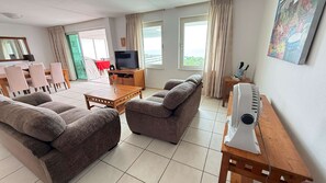 Een woonkamer met een zithoek, een televisie, een tafel en een radiator.