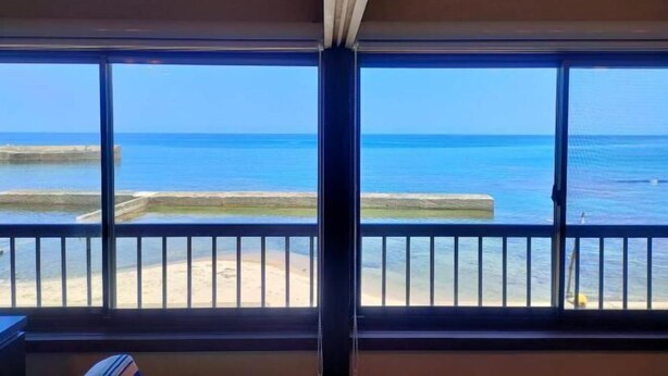 Una habitación con ventanas amplias que dan a una playa y al mar.