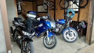 Eine Motorradgarage mit zwei Motorrädern, einem Helm und einem Fahrradständer.