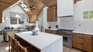 A modern kitchen with a central island, wooden cabinets, and a large window.