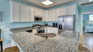 A kitchen with white cabinets, stainless steel appliances, granite countertops, and a breakfast bar. - Reunion Villas #3 - Four Bedroom Three Bath, Second Row with Community Pool (Garden City Beach)