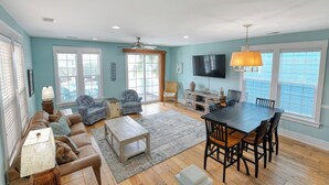 A spacious living room with a large dining table, comfortable seating, and a television. - Reunion Villas #3 - Four Bedroom Three Bath, Second Row with Community Pool (Garden City Beach)