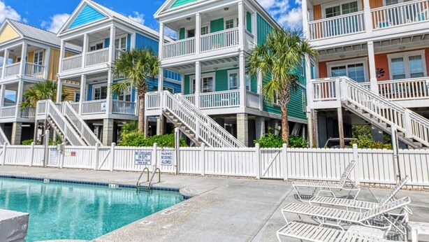 A beachfront hotel with multiple balconies, a swimming pool, and lounge chairs. - Reunion Villas #3 - Four Bedroom Three Bath, Second Row with Community Pool (Garden City Beach)