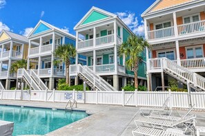 Un hôtel situé en bord de mer, doté de nombreux balcons, d’une piscine et de chaises longues.