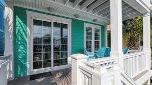A house with a green exterior, white porch, and a sliding glass door. - Reunion Villas #3 - Four Bedroom Three Bath, Second Row with Community Pool (Garden City Beach)
