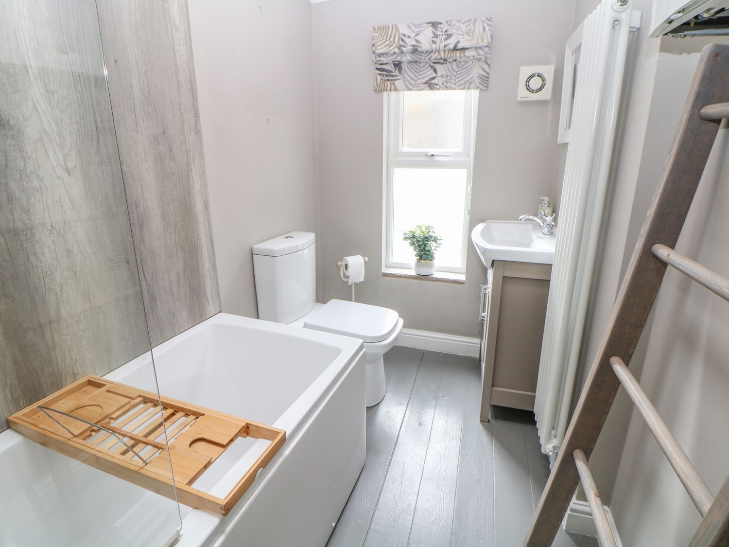 Ein Badezimmer mit Badewanne, Toilette, Waschbecken und einem Fenster mit Pflanze.