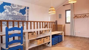 Ein Zimmer mit einer hölzernen Bank, einem blauen Stuhl und einer weißen Regaleinheit mit Aufbewahrungsbehältern.