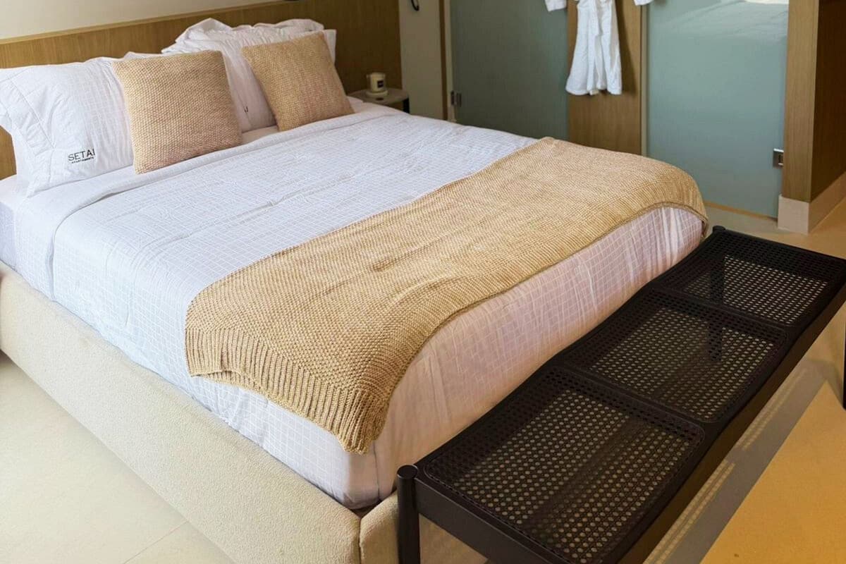 Een hotelkamer met een bed, een badjas hangend aan de deur en een airconditioner.