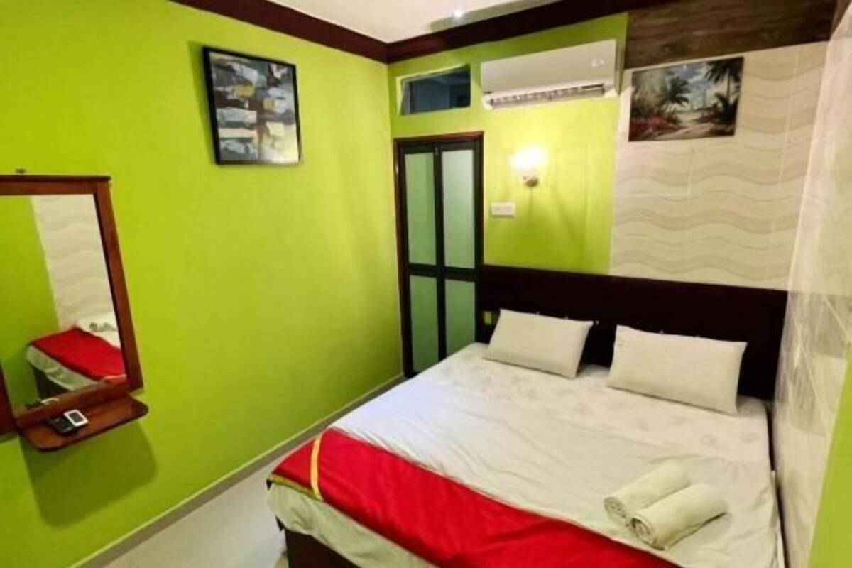 Ein Hotelzimmer mit einem Bett, einem Spiegel, einer Wand-Klimaanlage und einer Tür mit Glasfenster.