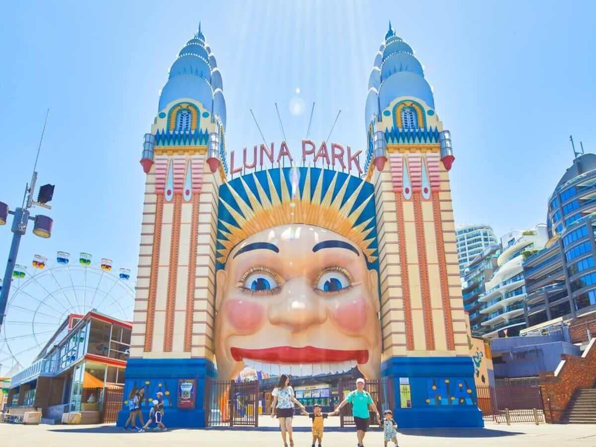 Luna Park's entrance with two towers, a Ferris wheel, and a large face sculpture.