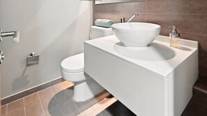 Ein modernes Badezimmer mit Toilette, großem Waschbecken und Handtuchhalter.
