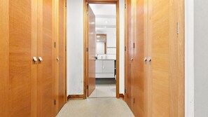A hallway with wooden doors leading to a kitchen area.