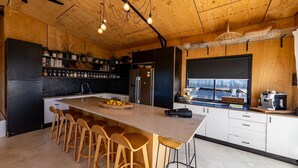 A modern kitchen with a central island, wooden bar stools, and a large window overlooking a scenic view. - Ocean View Escape - less than 5 min to the highway (Sandy Beach)