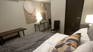A hotel room with a bed, a desk, a chair, a lamp, and a wardrobe. - Chill condo in San Fernando! (San Fernando)