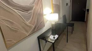 A hallway with a modern abstract painting, a table with a lamp, and a door at the end. - Chill condo in San Fernando! (San Fernando)