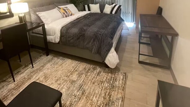 A modern hotel room with a bed, desk, chair, and a small table. - Chill condo in San Fernando! (San Fernando)