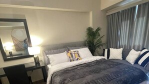 A modern hotel room with a large bed, a desk, and a chair. There is a mirror on the wall and a plant in the corner. - Chill condo in San Fernando! (San Fernando)