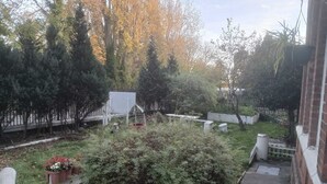 A garden with a wooden play structure, a white fence, and various shrubs. - Ground-Floor Family Studio Apartment with Double and Single Beds – Free Parking (Gosport)