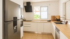 Una cucina moderna con elettrodomestici in acciaio inossidabile, mobili bianchi e una finestra che lascia entrare luce naturale.