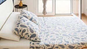 Una camera da letto con un letto, un comodino con lampada, una finestra con tende e vista su un balcone.