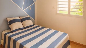 Una camera da letto con un letto, un motivo geometrico sul muro e una finestra con vista sul verde.